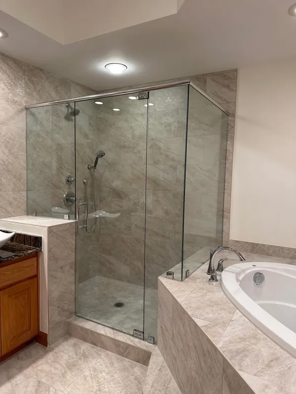 Glass corner shower on a knee wall with a header and chrome hardware