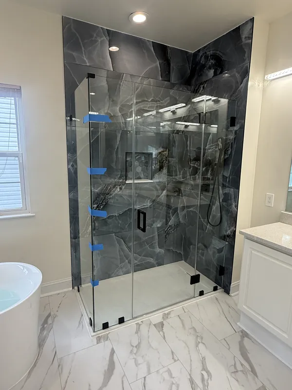 Frameless matte black shower enclosure seen from the bathroom entry