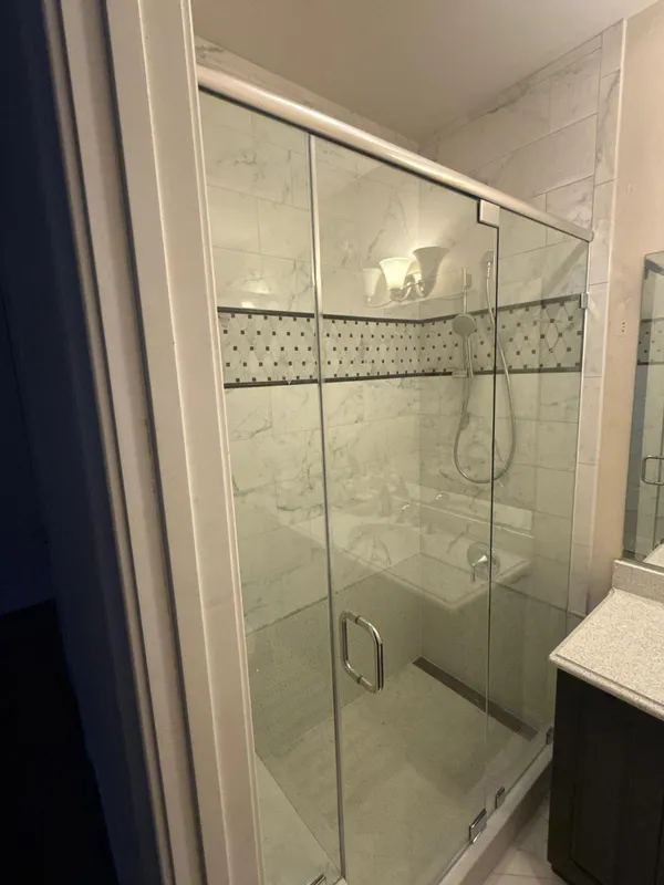 Frameless inline glass shower door with centered hinged door