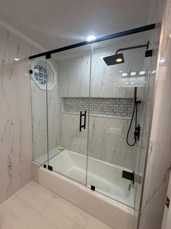 Frameless glass tub enclosure with matte black hardware