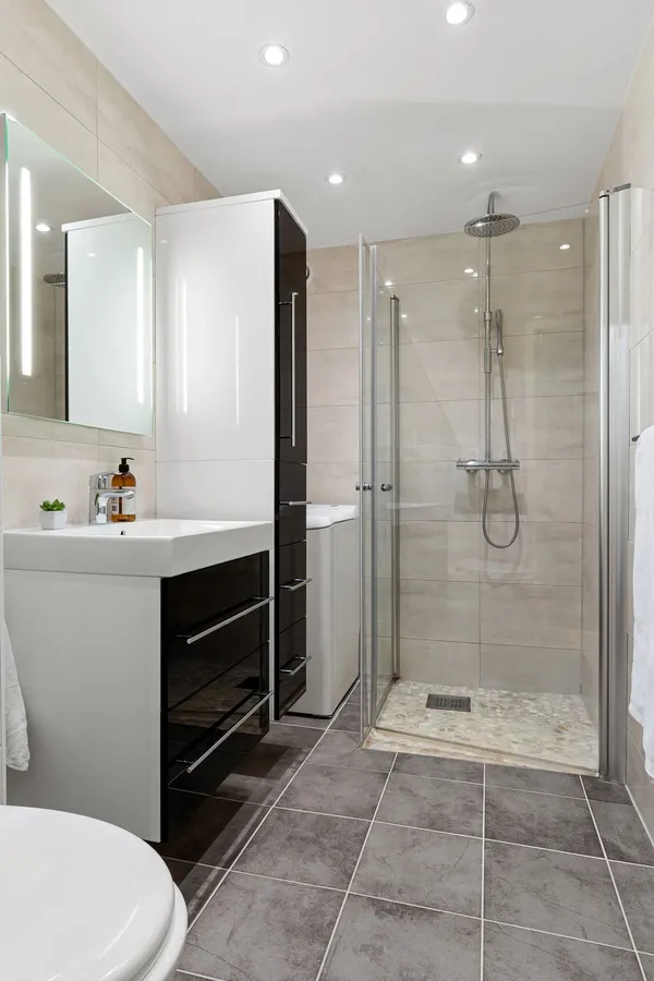 Semi-frameless glass shower enclosure in a tiled bathroom