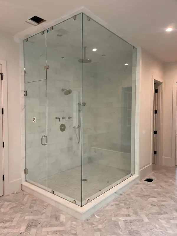 Tall frameless steam shower enclosure with glass transom and nickel hardware